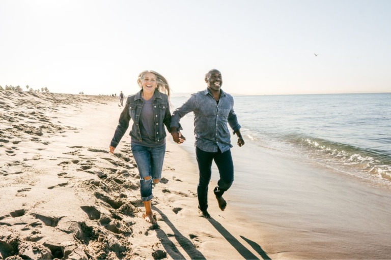 Happy couple jogging along the coastline of the beach