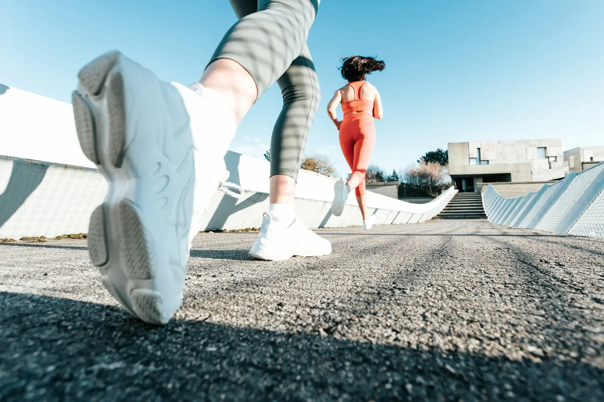 Closeup of sneaker and two athlets running on asphault track