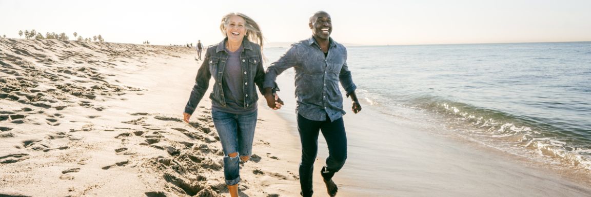 Happy couple jogging along the coastline of the beach