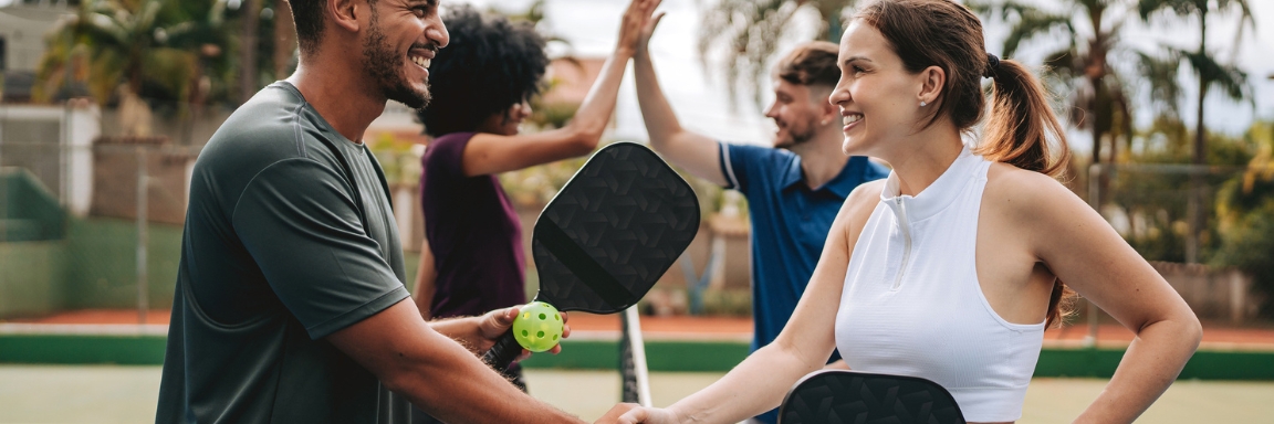 Friends playing pickleball on an outdoor court. Friends playing pickleball on an outdoor court.