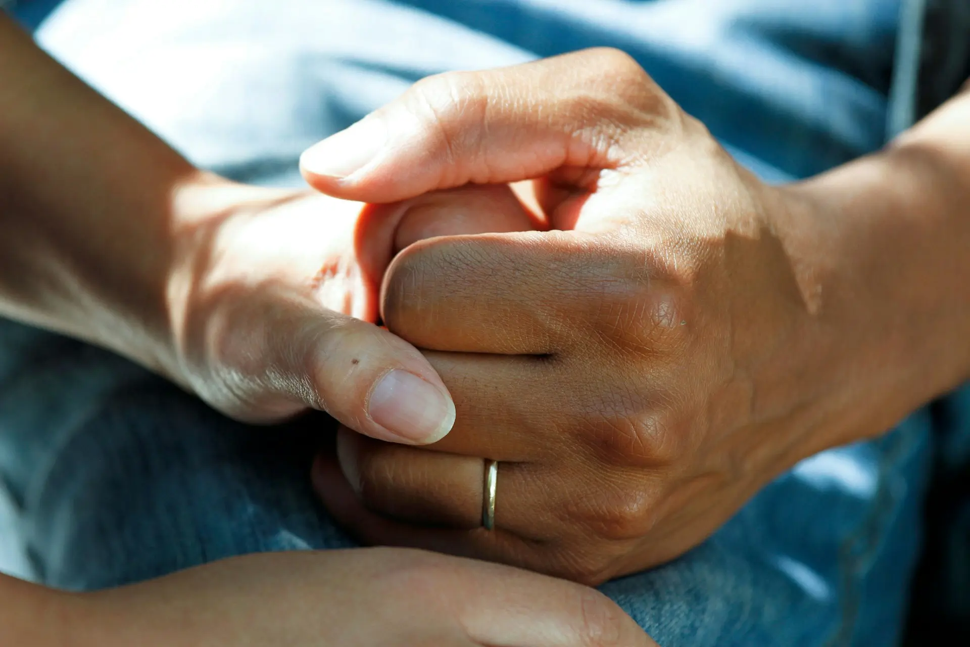Person clasping their hands tightly, representing chronic pain or inflammatory discomfort associated with autoimmune conditions.